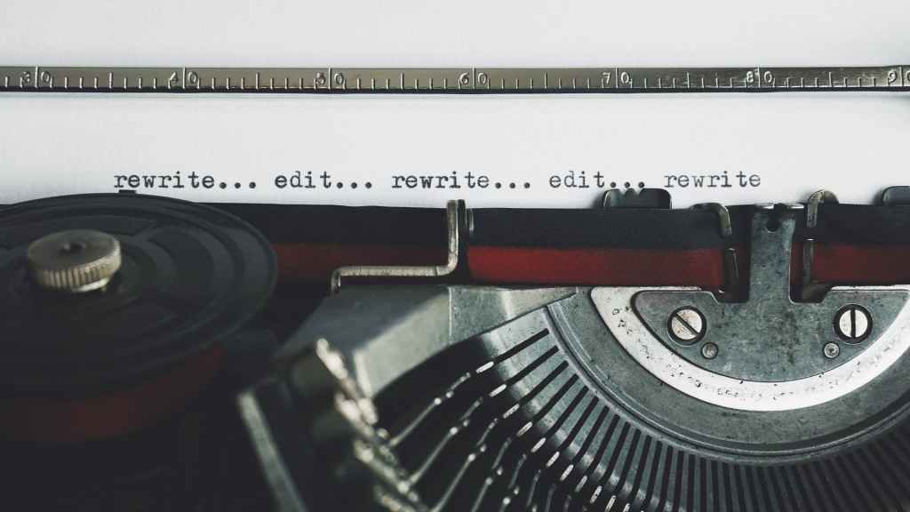 A close-up of an old-fashioned typewriter displays the words "rewrite...edit...rewrite...edit...rewrite"